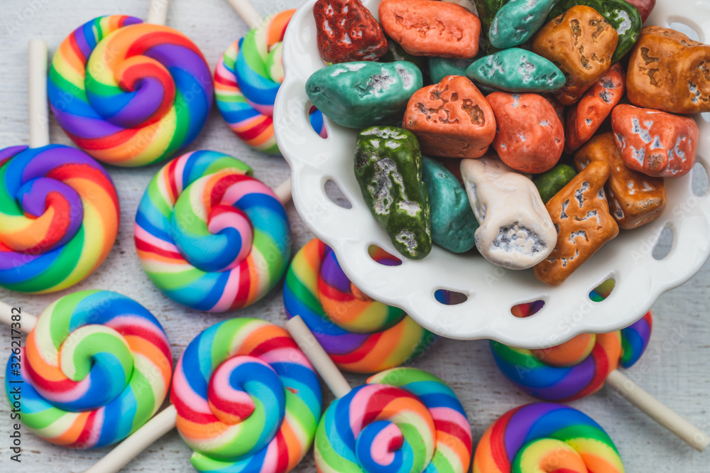 Candy pebbles in a bowl and lollipops. spiral candies and sweets in the form of colored stones