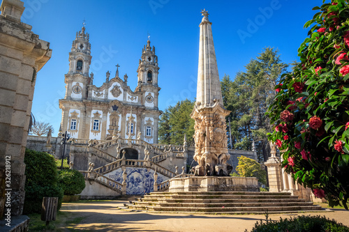 Nossa Senhora dos Remédios Sanctuary in Lamego, Portugal, with the church in the background and fountain with obelisk in the foreground, on a blue sky day. © Luis Fonseca