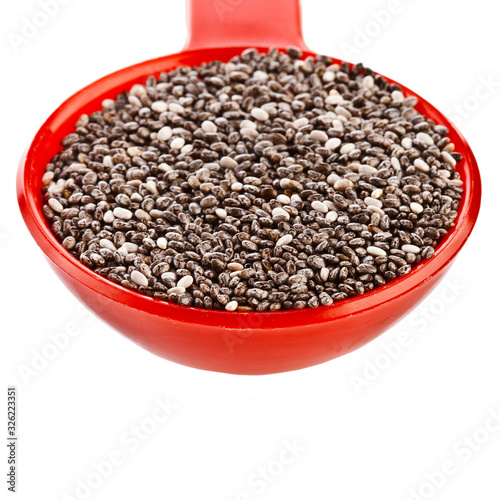 Chia seeds in a red plastic spoon isolated on a white background.