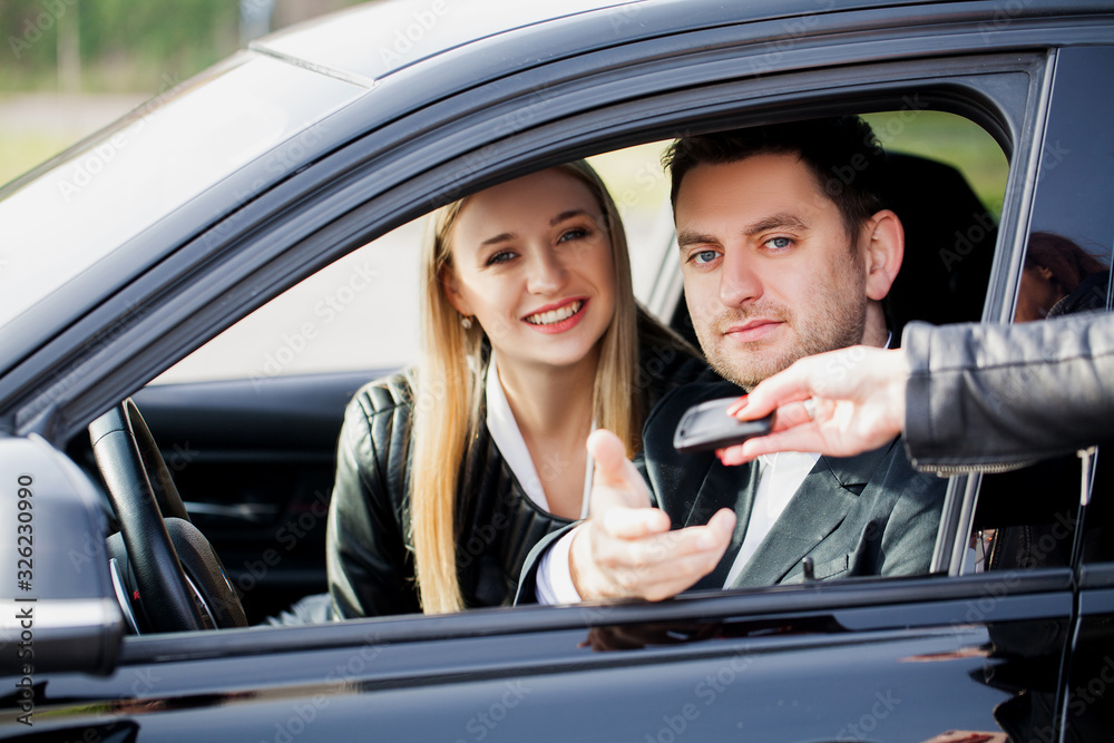 Happy young couple chooses and buying a new car for the family