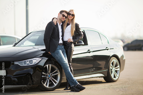 Happy young couple chooses and buying a new car for the family