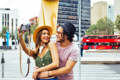 Portrait of a smiling young couple having fun taking selfie  looking at each other on street of Mexico City center photo