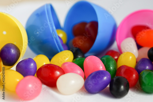 Colorful jelly beans spill out of a plastic Easter egg