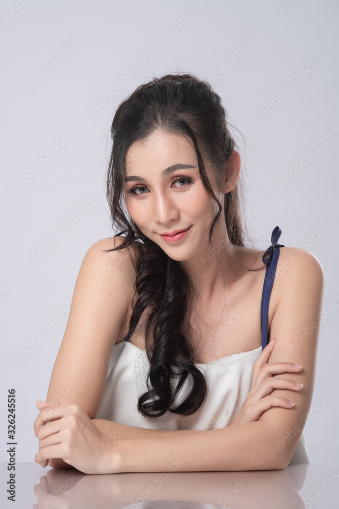 Portrait of asian beautiful smiling woman with natural make-up on grey background. Model look at camera. Portrait of asian beautiful smiling woman with natural make-up on grey background. Model look at camera.