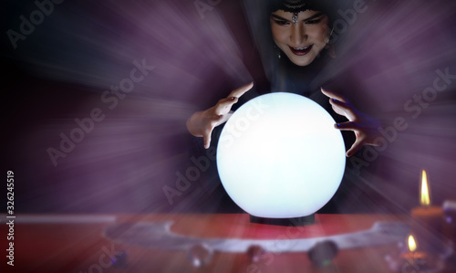 Fortune Teller's young Asian woman is predicting the future and destiny with crystal ball. Her hands are around the crystal ball.