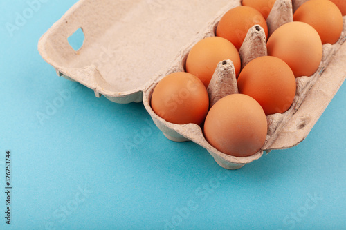 Egg Chicken eggs. Top view of an open gray box with brown eggs Isolated on a blue background. The concept of a healthy lifestyle, getting pure protein. Proper Breakfast. Dissati eggs. photo