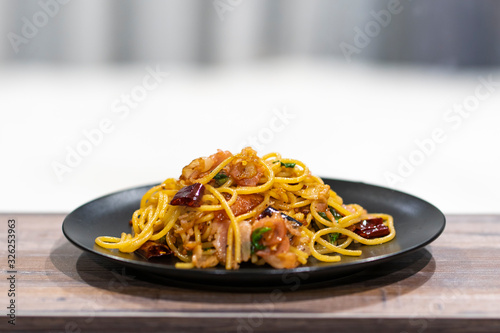 selective focus at center of black Plate of delicious spaghetti Bolognaise or Bolognese with savory minced beef on the wooden table with white background.