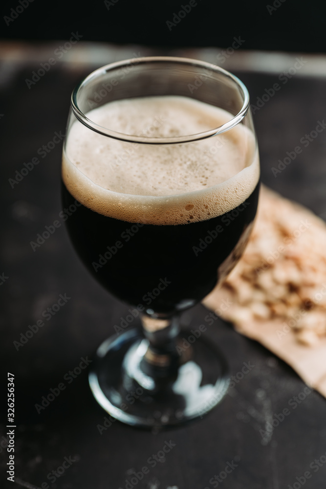 Freshly brewed dark beer on the black rustic background. Selective focus. Shallow depth of field. Freshly brewed dark beer on the black rustic background. Selective focus. Shallow depth of field.