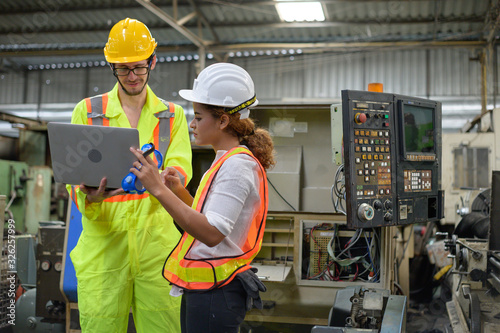 Caucasian male with laptop and mixed race female engineer working in factory area.