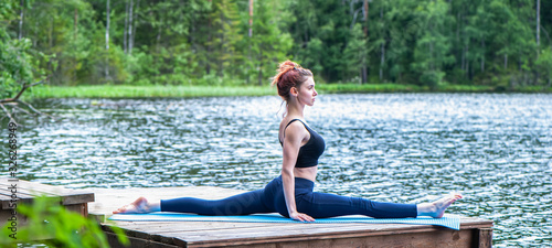 Young yogi  girl  practicing yoga, stretching in Monkey God exercise, Splits, Hanumanasana pose on the lake. The concept of appeasement,  healthy lifestyle. photo