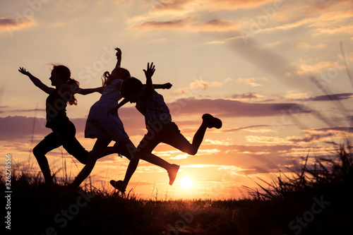 Happy children playing in the park at the sunset time.