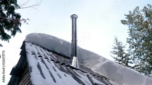 Close-up shot of smoke coming from a chimney on the roof of an residential building in a Siberian village. Metal smokestack on the rooftop of a house in Siberia. 4K photo