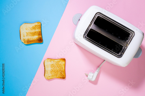 Toaster and bread slices Cooking bread in a toaster on a pink background close up. top view