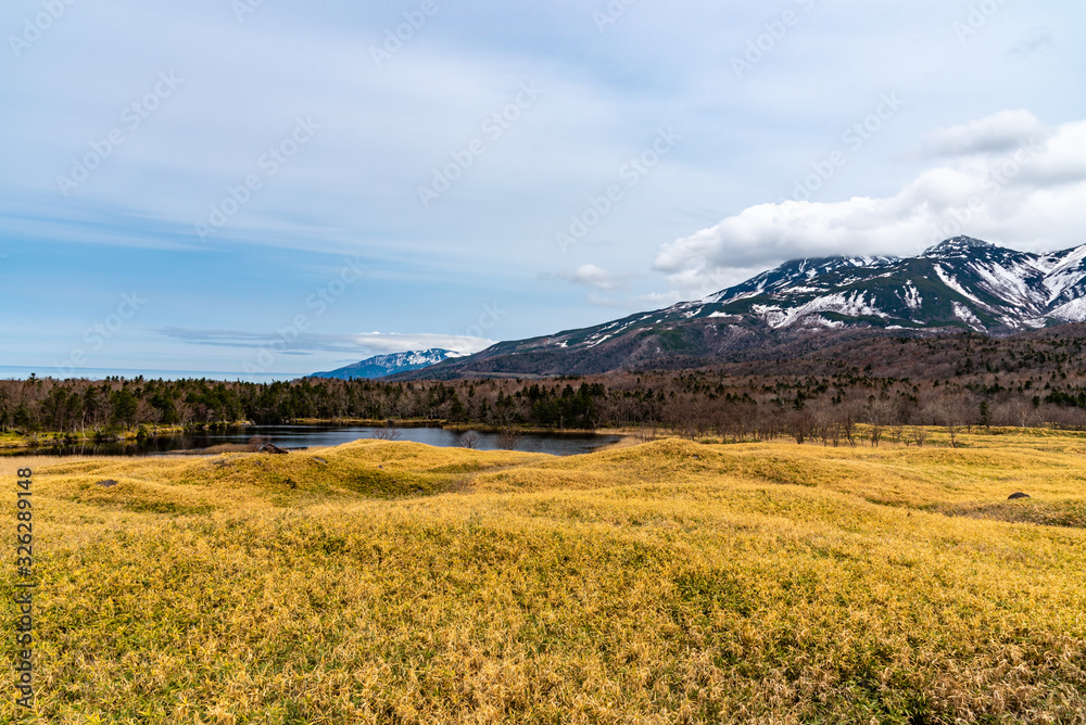 Obraz premium Beautiful lake and rolling mountain range on springtime sunny day. High latitude country natural beauty scenery. The First Lake of Shiretoko Goko Five Lakes, Shiretoko National Park. Hokkaido, Japan