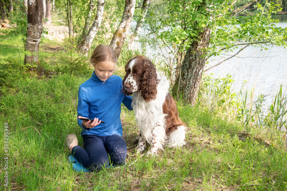 A young girl shows something to her dog in a mobile phone. A child plays with a dog and telephone A young girl shows something to her dog in a mobile phone. A child plays with a dog and telephone