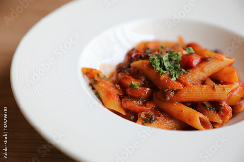 Penne arrabiata pasta tomato sauce with spices italian food on wood background