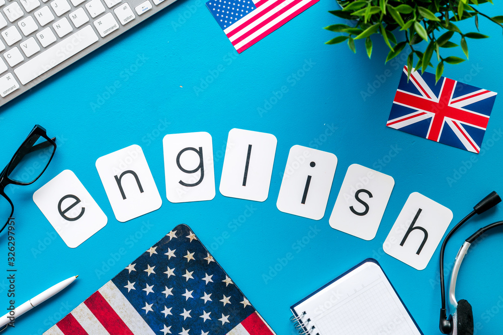 Obraz premium Learn English online. Concept with text, headset and keyboard on blue background top-down