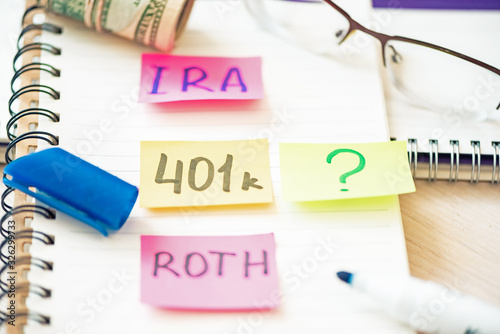 401k ira roth on pieces of colorful paper dollars on table. Pension concept. Retirement plans.