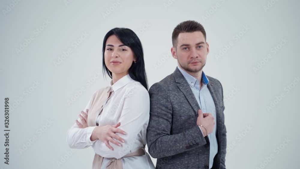 Partners leaning back to back. Young man and woman standing back to back with crossed hands against gray background Partners leaning back to back. Young man and woman standing back to back with crossed hands against gray background