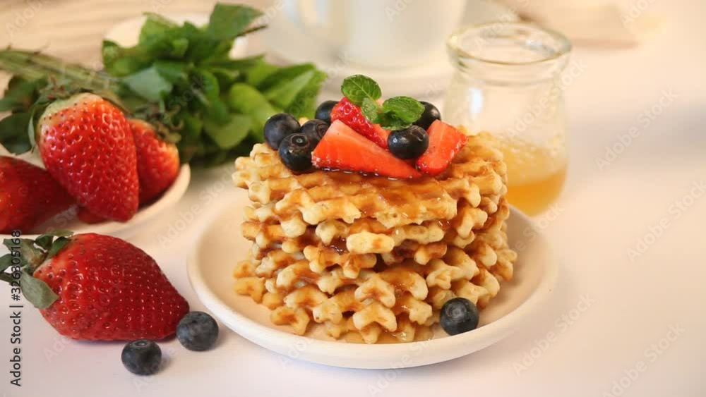 Honey pouring on a tasty waffles with berries Honey pouring on a tasty waffles with berries