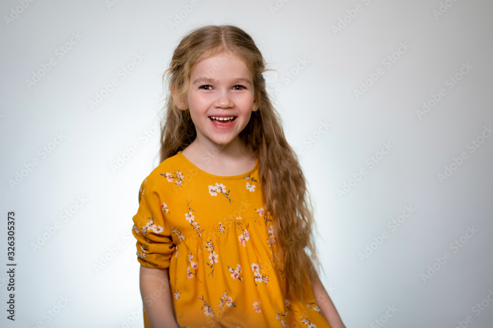 little girl in yellow dress laughing on white back little girl in yellow dress laughing on white back