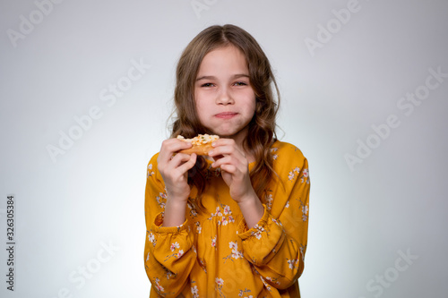 teen girl biting and eating pizza, mouth full.
