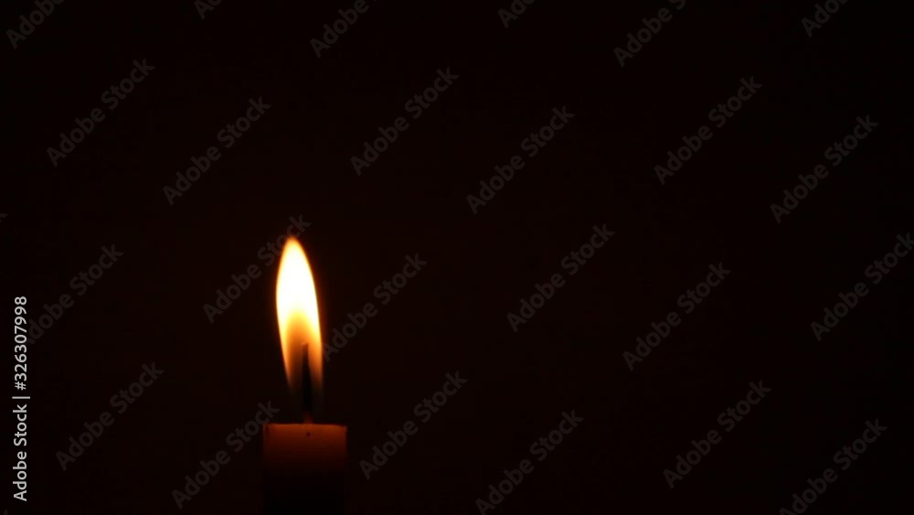 Close-up of a Candlelight Isolated on a Black Background, candlelight moves in the wind Close-up of a Candlelight Isolated on a Black Background, candlelight moves in the wind