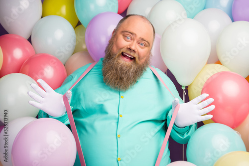 Portrait of careless playful man funny funky hipster enjoy anniversary party celebration pull pink suspenders wear teal shirt over air baloons background © deagreez