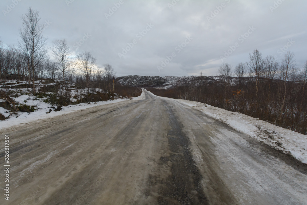 Obraz premium The dirt road is covered with ice .The sky is covered with clouds.