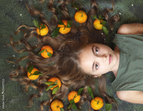 The image of a beautiful girl with tangerines in her hair under the falling snow
