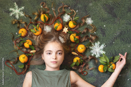 The image of a beautiful girl with tangerines in her hair under the falling snow