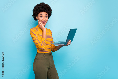 Profile photo of pretty dark skin curly lady hold notebook hands reading good news modern technology user wear yellow striped jumper isolated blue color background photo