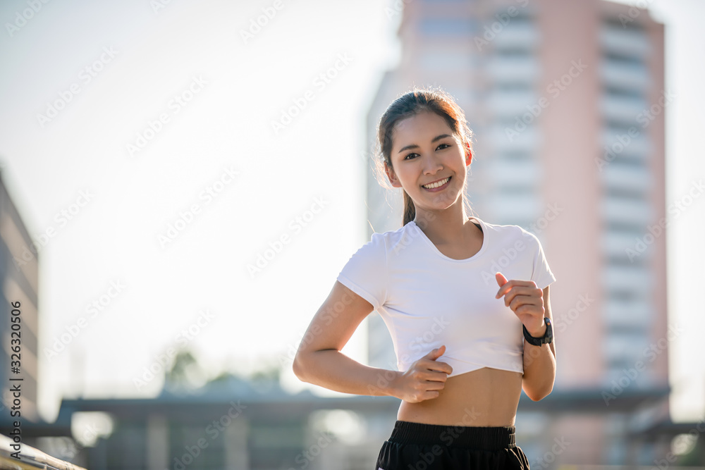 Asian Young fitness sport woman running  and smiling on city road
