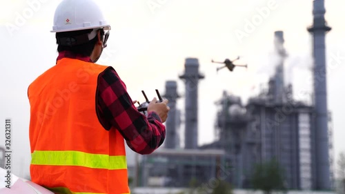 Asian construction worker piloting drone at building site. video surveillance or industrial inspection