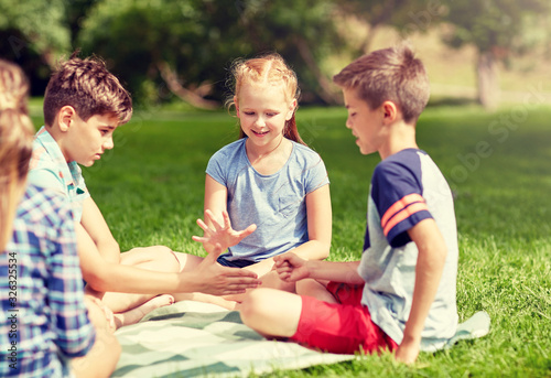 summer holidays, entertainment, childhood, leisure and people concept - group of happy pre-teen kids playing rock-paper-scissors game in park © Syda Productions