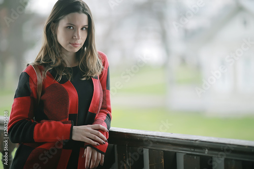 autumn sad girl outdoor / autumn weather, portrait of a young adult girl in a coat in a cage, Scottish style