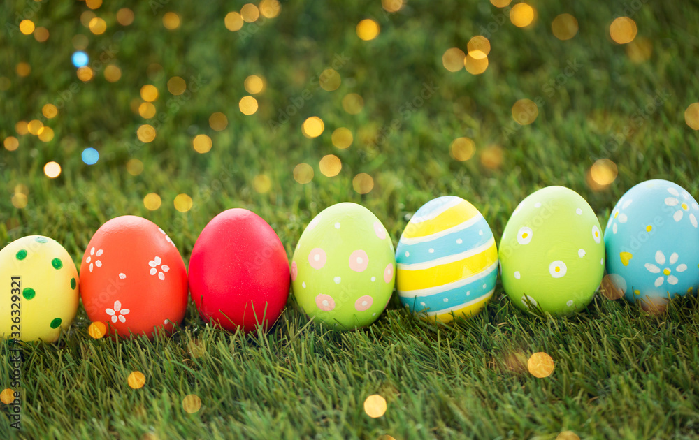 Fototapeta premium easter, holidays and tradition concept - row of colored eggs on artificial grass