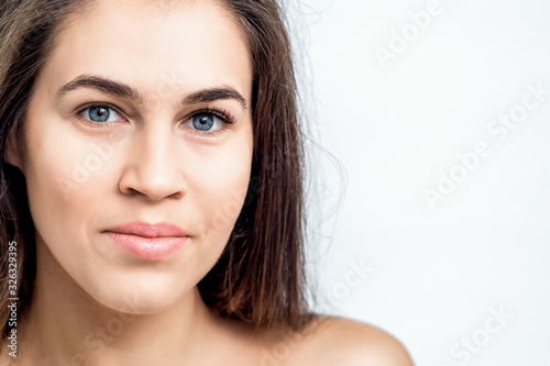Portrait of a beautiful woman s natural makeup face and naked shoulders with clean skin on white background with copy space.