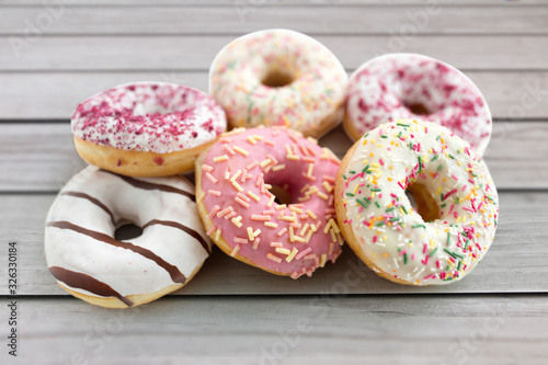 sweet food, junk-food and unhealthy eating concept - close up of glazed donuts over grey wooden boards background