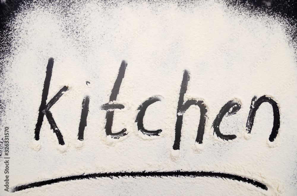 words Kitchen written on a black background with flour. Inscription. words Kitchen written on a black background with flour. Inscription.