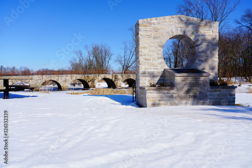 Stone Arch way walking path bridge at Riverside park in St. Cloud, Wisconsin covered in snow during Winter season.  © Aaron