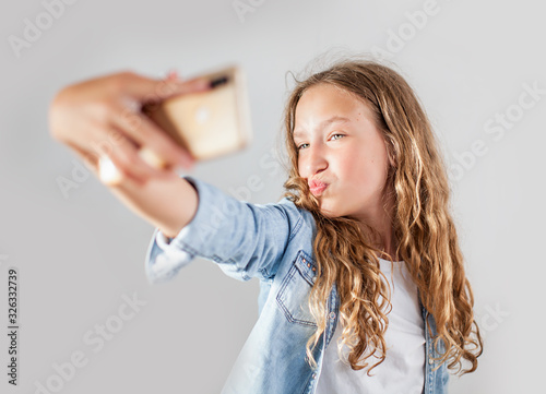 Smiling teen making selfie photo on smartphone over white background cute girl