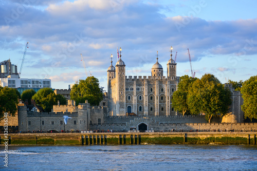 Colourful view of the Tower of London, a castle and a former prison in London, England, from the River Thames at sunset. The Tower of London, today a museum, houses a collection of crown jewels