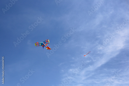 Show kites. Multi-colored kite in the blue sky. Colored kite plane