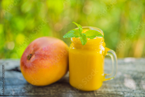 Mango smoothie in a glass Mason jar and mango on the old wooden background. Mango shake. Tropical fruit concept