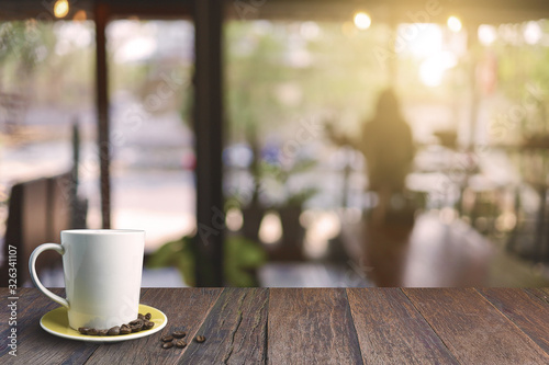 Wood table top with white coffee cup in coffee shop background.  In the morning  vintage style effect picture