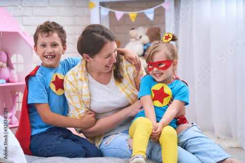 Happy family. A young woman plays with her children in superheroes.