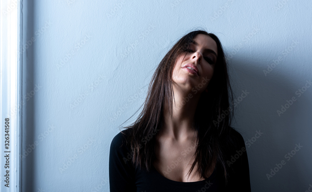 Dark mood portrait of a woman in front of a wall Dark mood portrait of a woman in front of a wall