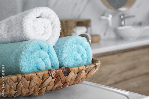 Wicker tray with clean soft towels in bathroom, closeup