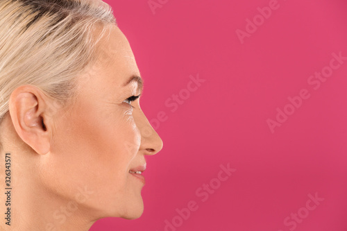 Portrait of beautiful mature woman on pink background, closeup. Space for text